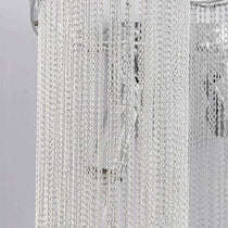The Cadena chain tassel wall sconce by Morsale.com lit in a living room, modern stainless steel and aluminum.