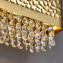 The Bern crystal wall sconce by Morsale.com illuminated in a hallway, gold frame with clear K9 crystal.