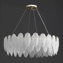 The Foglia chandelier by Morsale.com lit in a dining room, leaf-cut art glass glowing warm on stainless steel.