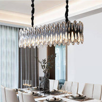 The Napoli crystal dining chandelier from Morsale.com casting a warm glow over a table, K9 crystal on polished steel.