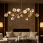 Diamante 15-pendant modern chandelier by Morsale.com, fifteen clear crystal orbs suspended from a warm copper frame above a dining table.