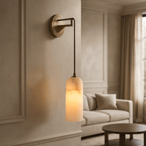 Lucera sconce with glowing marble shade on a brass arm